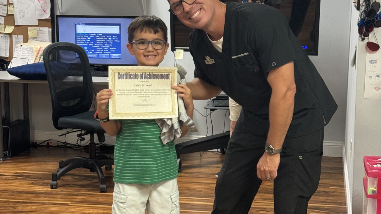 Caleb holding his graduation certificate with Dr. Thomas