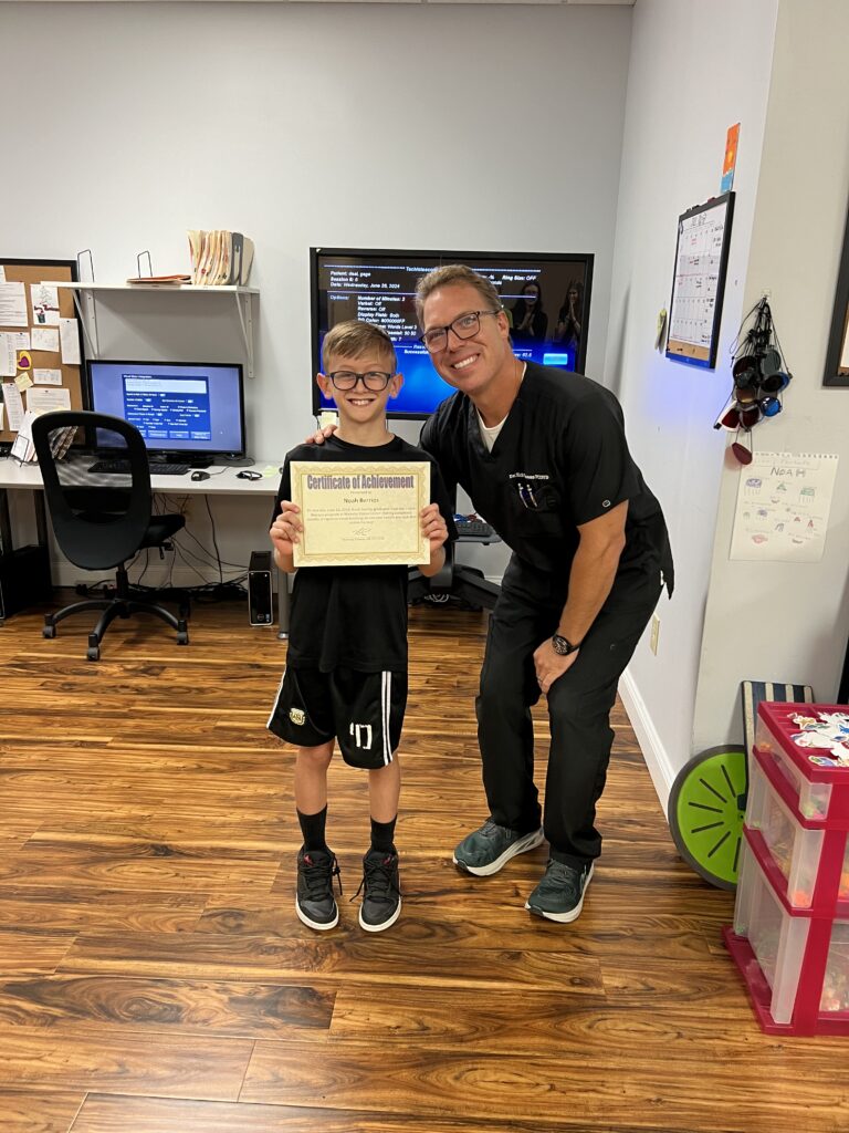 Noah holding his Certificate of Achievement beside Dr. Thomas on graduation day